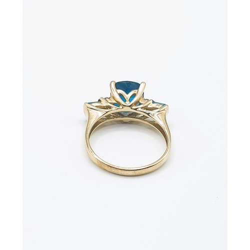 300 - A 9ct yellow gold and blue topaz ring, set with a faceted cushion-cut bright blue topaz, four-claw s... 