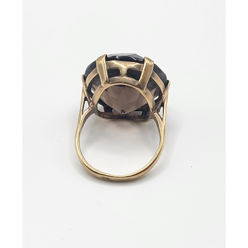 301 - A 9ct yellow gold and smoky quartz cocktail ring, set with a large round-cut quartz, measuring appro... 