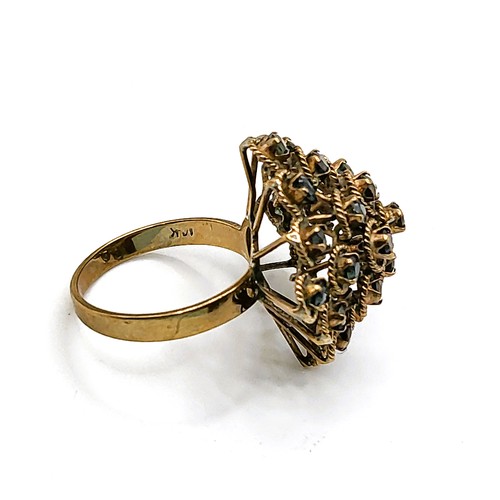 303 - A yellow metal and sapphire domed cluster ring, the round-cut sapphires within slender rope-twist mo... 