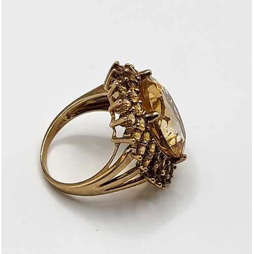 310 - A 9ct yellow gold and citrine cocktail ring, set with a large mixed oval-cut stone within a double b... 