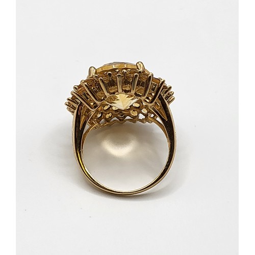 310 - A 9ct yellow gold and citrine cocktail ring, set with a large mixed oval-cut stone within a double b... 