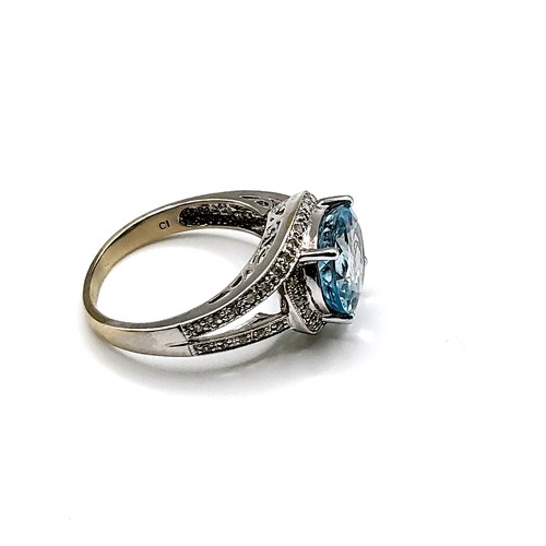 318 - An 14ct white gold and pale blue topaz cocktail ring, surrounded with diamond accents, size R 1/2.