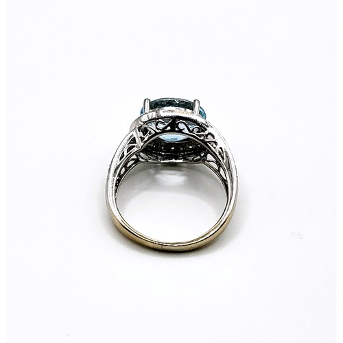 318 - An 14ct white gold and pale blue topaz cocktail ring, surrounded with diamond accents, size R 1/2.