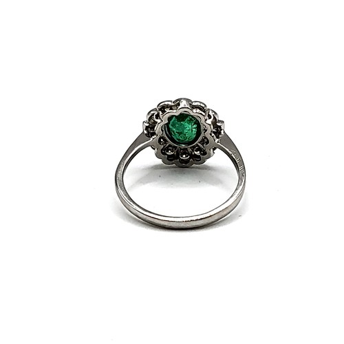 326 - An emerald and diamond cluster ring, set with an oval-cut emerald of approximately 1.20 carats, the ... 