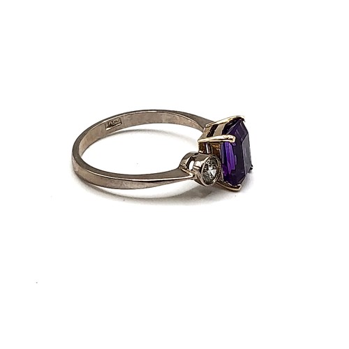 330 - An 18ct white gold, diamond, and amethyst three stone ring, set with a rectangular-cut amethyst flan... 