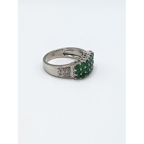 347 - An 18ct white gold, diamond, and emerald ring, set with twenty-one round-cut emeralds, the shoulders... 