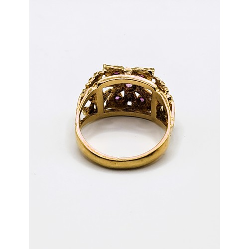 386 - A yellow metal and ruby ring, centred with a collet-mounted ruby, and six smaller rubies, indistinct... 