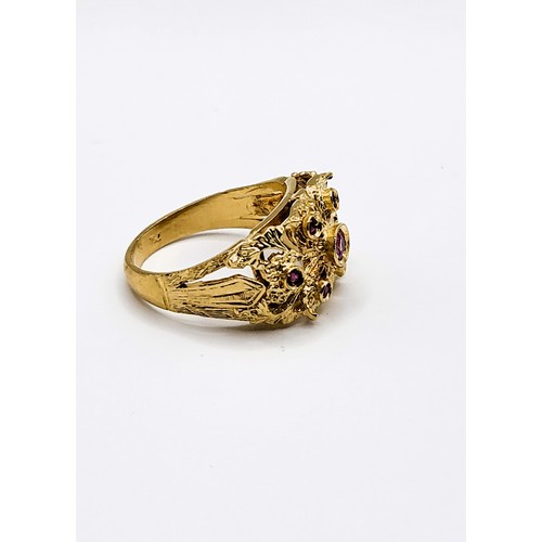 386 - A yellow metal and ruby ring, centred with a collet-mounted ruby, and six smaller rubies, indistinct... 