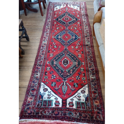 67 - A rich red ground Persian Hamadan runner, full pile with medallion design. 300cm x 98cm.