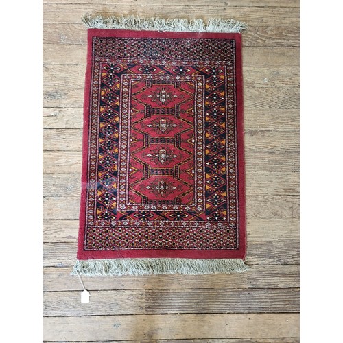 69 - A red ground prayer rug, double bordered and fringed. 103cm x 65cm