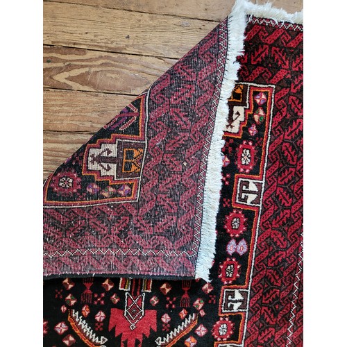 70 - A red and black ground rug with symmetric pattern detail, fringed. 208cm x 91cm