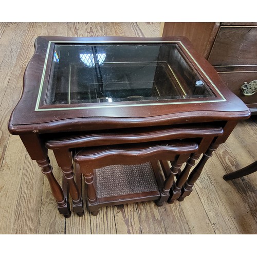 24 - A nest of three modern tables with glass insert top and rattan shelf.