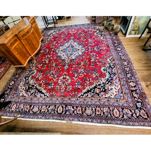 76 - A large red and blue ground rug with central medallion design, multi-bordered and fringed. 330cm x 4... 