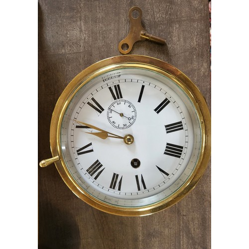 73 - A Victorian brass ship's clock with key. 17cm diameter.