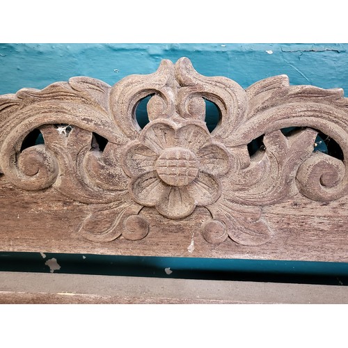 18 - An ornately carved wooden garden bench. 98cm x 120cm x 52cm