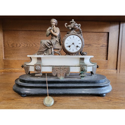 73 - An ornate mantle clock, the white dial beside the seated figure of a Classical woman, raised on whit... 