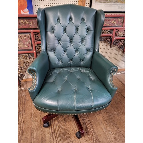 65 - A green leather swivel office chair, with green leather buttoned upholstery, supported on pedestal b... 