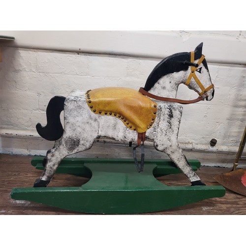 113 - A dabble grey rocking on horse with leather saddle on a green rocking base. 80cm x 95cm x 28cm.