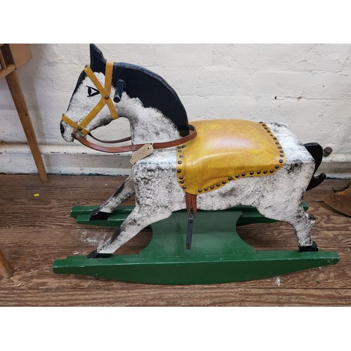 113 - A dabble grey rocking on horse with leather saddle on a green rocking base. 80cm x 95cm x 28cm.