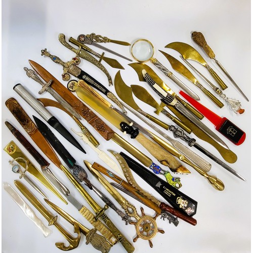 119 - A collection of paper knives with varying heads including owl, elephant, duck, magnifying glass, pee... 