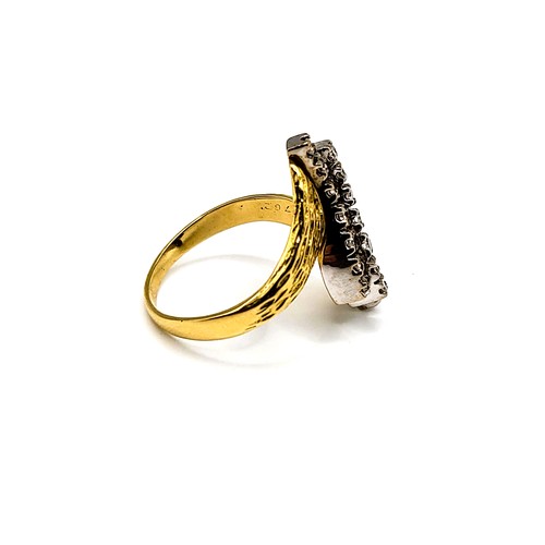 242 - A yellow metal and diamond crossover ring, the textured shoulders set with three rows of round brill... 