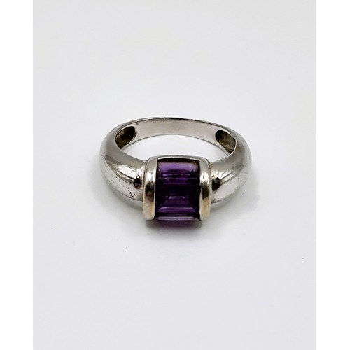 254 - An 18ct white gold ring with three baguette cut purple gemstone, channel set, 4.6g,