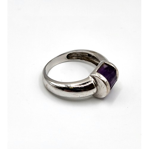 254 - An 18ct white gold ring with three baguette cut purple gemstone, channel set, 4.6g,