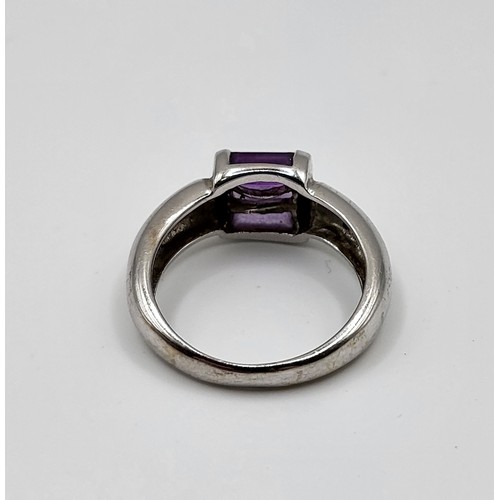 254 - An 18ct white gold ring with three baguette cut purple gemstone, channel set, 4.6g,