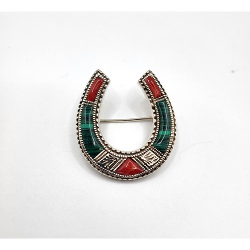 268 - A silver horseshoe brooch set with malachite and red jasper. 6g. 3.5cm x 3cm.