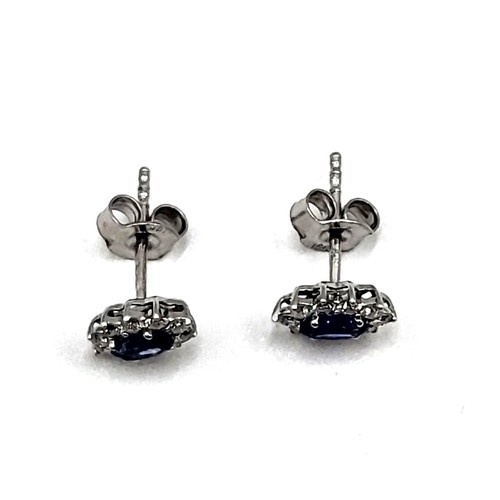 272 - A pair of 18ct white gold sapphire and diamond cluster earrings of 1.1cts total. Approc 0.8cm x 0.6c... 