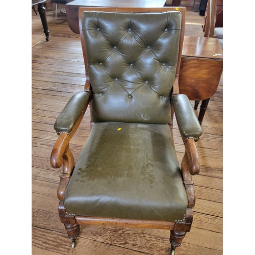 28 - A leather reclining armchair, button back, padded arm rests with studs and turned legs on casters. 9... 