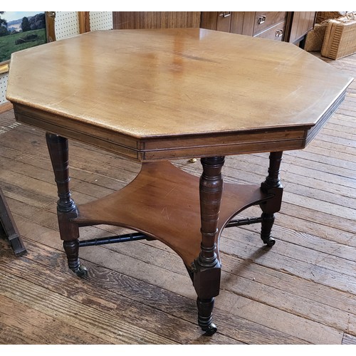 31 - Edwardian octagonal centre table with low shelf over cross stretcher and on castors. 70cm x 90cm x 9... 