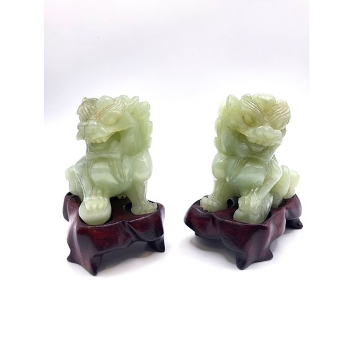 123 - A pair of Jadeite Chinese Dragon Dogs on wooden stands in good condition. 7cm 328gms excluding stand... 