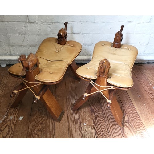 53 - Two camel saddle stools circa 1930's. Each stool has a carved wooden camel at each end, padded butto... 