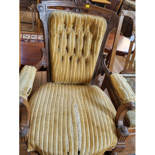 7 - A Victorian carved armchair button-back, padded arm rests, seat upholstery in needs of repair, on ca... 