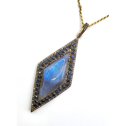 381 - A large rhomboid pendant in yellow metal set with an oval cabochon labradorite surrounded by sapphir... 