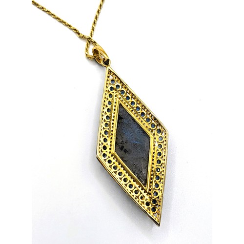 381 - A large rhomboid pendant in yellow metal set with an oval cabochon labradorite surrounded by sapphir... 