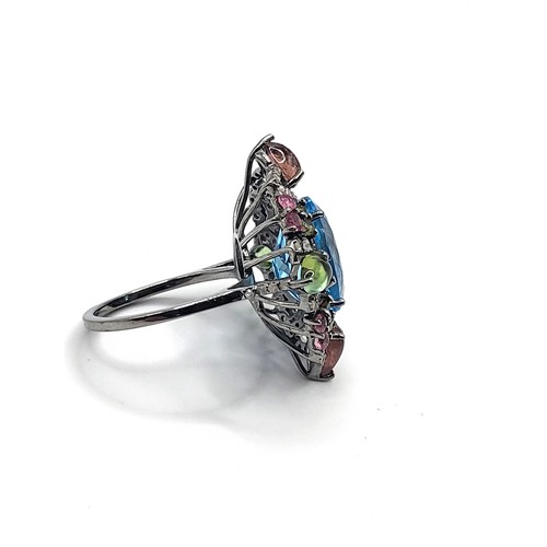 388 - A large dress ring set with an oval-cut Swiss blue topaz, pear-cabochon pink and green tourmalines, ... 