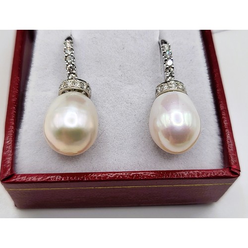 393 - A pair of 18ct white metal (unmarked) oval cultural pearl and round brilliant diamond collar and bal... 