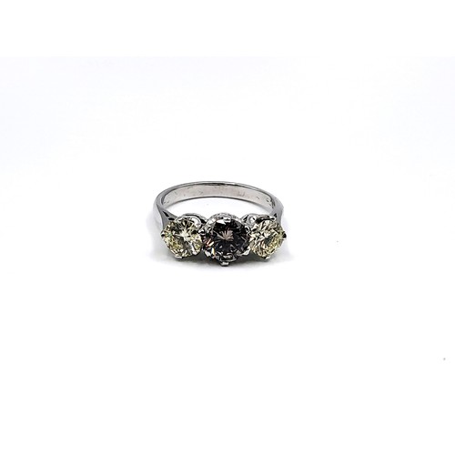 398 - A marked 18ct white gold three stone diamond ring the central cognac coloured.  2.08cts total. 4.3gm... 