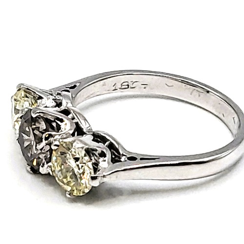 398 - A marked 18ct white gold three stone diamond ring the central cognac coloured.  2.08cts total. 4.3gm... 