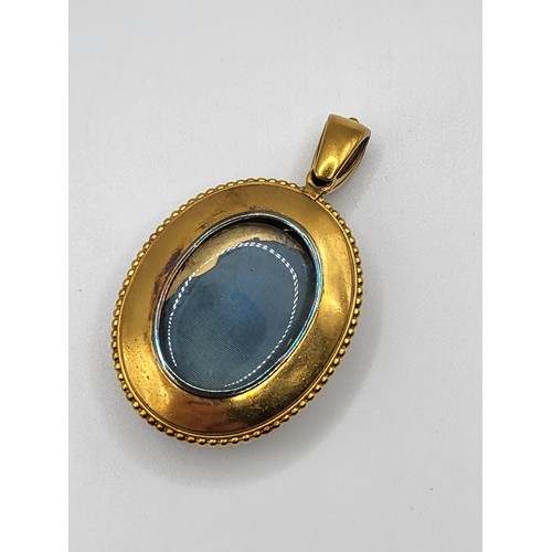 412 - A Victorian glass top pendant/ memento mori locket in gilt metal, and three brooches including a ova... 