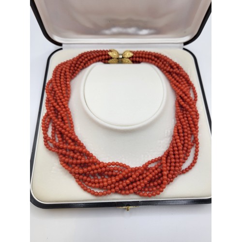 416 - A multi-strand orange-red glass beaded choker necklace with an 18ct twist clasp and leaf motif caps ... 