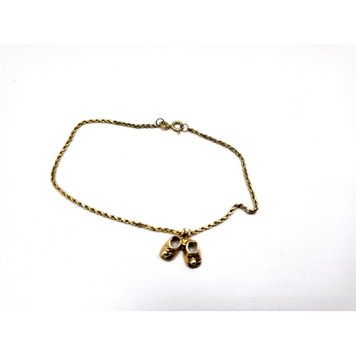 423 - A 14ct yellow gold diamond cut  rope chain bracelet with a pair of babies booties (14ct).  2gms 18cm... 