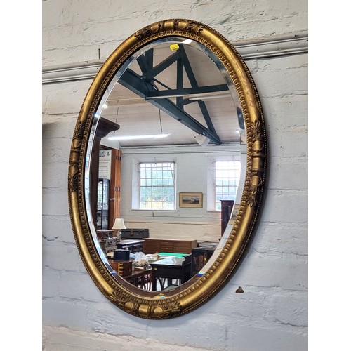 9 - A bevelled oval mirror in a wooden frame 86cm x 60cm.