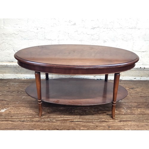 11 - A 1970's dark wood oval coffee table with lower shelf. 46cm x 97cm x 57cm.