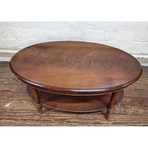 11 - A 1970's dark wood oval coffee table with lower shelf. 46cm x 97cm x 57cm.