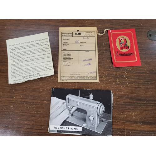 8 - A vintage PFAFF sewing machine and table with tapered legs, and  guarantee and instructions booklet.... 