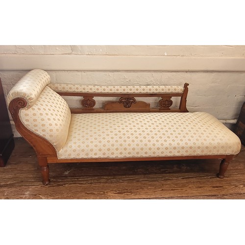 15 - A carved oak chaise longue with cream upholstery. 75cm x 170cm x 63cm.