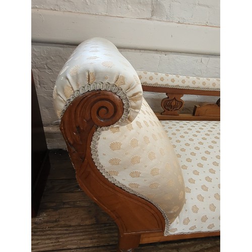 15 - A carved oak chaise longue with cream upholstery. 75cm x 170cm x 63cm.